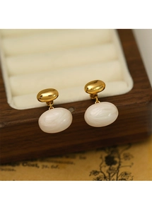 Détail de boucles d'oreilles dorées avec pierres marbrées sur un coffret bijoux