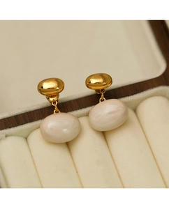 Gros plan de boucles d'oreilles boules dorées avec perles blanches en boîte
