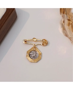 Detail of vintage gold brooch with an octagonal Athena coin pendant and crystal border