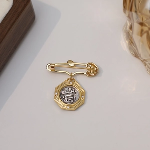 Retro Athena coin brooch with gold octagonal frame and rhinestone details on light wood