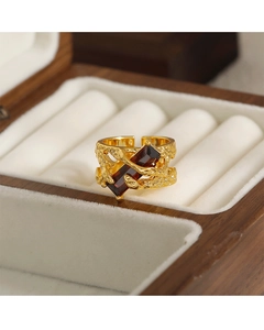 Detalle de anillo vintage dorado con piedra roja rectangular y banda con relieve