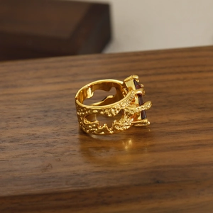 Anillo vintage dorado con textura de lava y gema roja sobre fondo de madera rústica