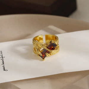 Anillo vintage dorado con textura de lava y gema roja rectangular en diseño abierto