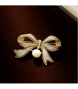 Detailed macro of vintage bow brooch with micro-pave zircons and white pearl drop