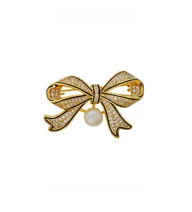Macro shot of vintage gold bow brooch with pavé zircon stones and a hanging white pearl