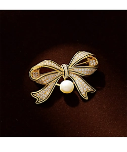 Macro detail of vintage bow brooch with pavé zircon stones and a hanging white pearl