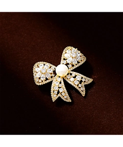 Detail of cubic zirconia bow brooch with large central pearl and gold-plated finish