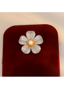 Détail macro d'une broche fleur en argent avec pétales en zircon et perle centrale