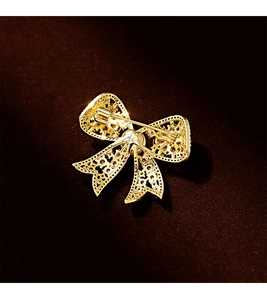 Detailed view of the gold-tone bow brooch back featuring intricate filigree and secure pin