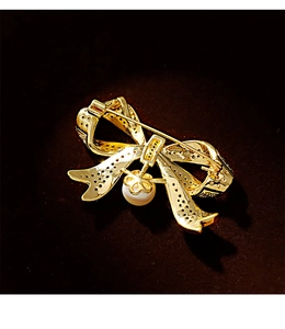 Close-up of vintage gold bow brooch with sparkling crystals and a white pearl pendant
