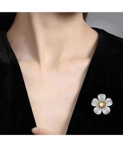 Gros plan d'une broche fleur en zircone avec une perle centrale sur une robe noire