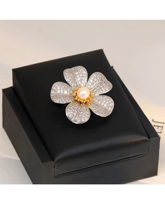 Détail macro d'une broche fleur en zircon et perle sur une boîte à bijoux noire