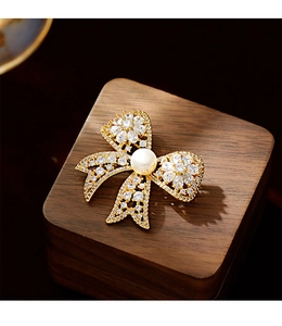 Macro shot of gold bow brooch with sparkling cubic zirconia and white freshwater pearl