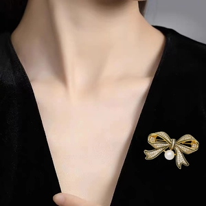 Vintage gold bow brooch with sparkling crystals and pearl on black velvet blazer