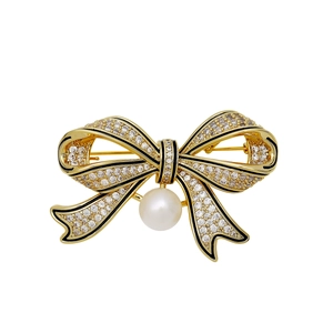 Vintage gold bow brooch with black enamel, cubic zirconia, and a hanging pearl drop