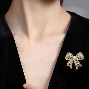 Elegant bow brooch with pavé cubic zirconia and freshwater pearl on black velvet jacket