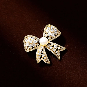 Elegant gold bow brooch with sparkling cubic zirconia and white freshwater pearl accent