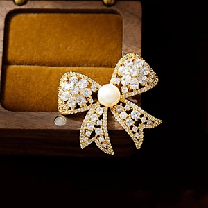 Elegant bow brooch with cubic zirconia and freshwater pearl on wooden jewelry box