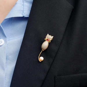 Broche chat dorée avec cristaux, rubis rouge et perle sur un revers de veste noir