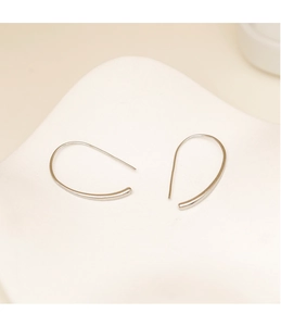 Primer plano de pendientes geométricos de plata minimalistas con acabado metálico pulido