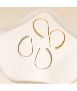 Detalle de pendientes de gota minimalistas en dorado y plateado en bandeja blanca