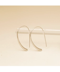 Detalle de pendientes en U plateados con acabado mate sobre soporte transparente