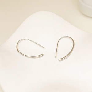 Pendientes de gota geométricos plateados minimalistas en una bandeja blanca decorativa