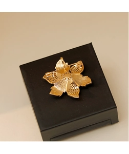 Vue détaillée du dos de la broche fleur dorée montrant le fermoir et la texture du métal