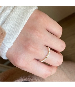 Detailed view of handmade stretch pearl ring with small gold bead on finger