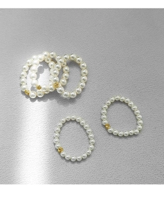 Close-up of handmade pearl rings with elegant golden beads on a grey textured surface