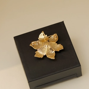 Vue arrière de la broche fleur vintage dorée montrant l'épingle et les textures évidées