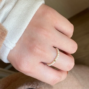 Minimalist pearl beaded ring with gold accent bead worn on finger for a stylish look