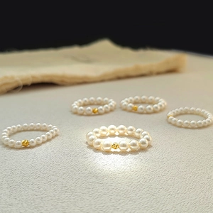 Five-piece set of elegant white pearl elastic rings with spiral golden bead accents