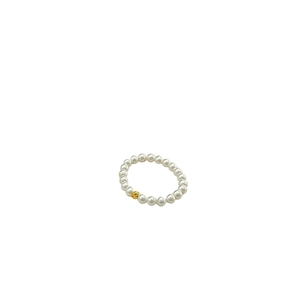 Minimalist pearl beaded ring with golden wave charm on white elastic cord band