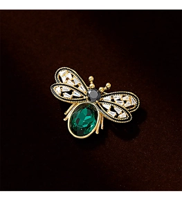 Detailed close-up of a luxury gold bee brooch with green crystal and zircon inlay