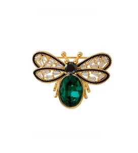 Detail of cute bee brooch with green emerald gemstone and black enamel gold wings