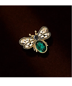 Macro detail of a bee brooch with green gemstone and sparkling crystal wings