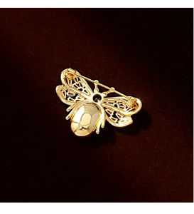 Detail view showing the secure gold safety pin fastener and filigree wing craftsmanship