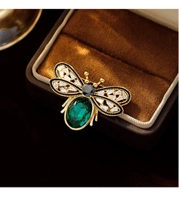 Macro shot of a vintage gold bee brooch with emerald gemstone and crystal wings