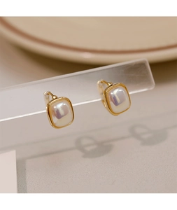Macro shot of minimalist gold rectangular hoop earrings with iridescent pearl centers