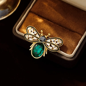 Elegant gold bee brooch with green oval gemstone and crystal wings on velvet box