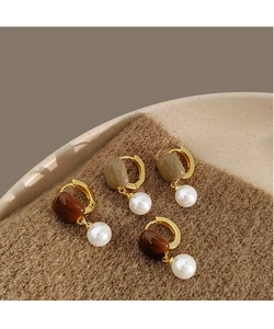Détail de boucles d'oreilles vintage avec résine brune et perles blanches