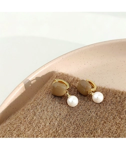 Détail de boucles d'oreilles perles dorées vintage avec accents carrés marron