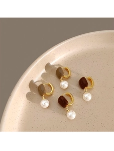 Détail de boucles d'oreilles Maillard vintage avec créoles dorées, résine brune et perles