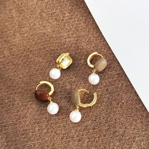Boucles d'oreilles créoles dorées vintage avec pierre brune et perles sur fond peluche