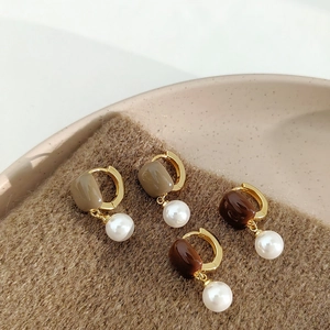 Boucles d'oreilles rétro en perles dorées avec émail marron sur fond en tricot chic