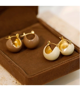 Détail de boucles d'oreilles créoles émaillées crème et caramel sur velours