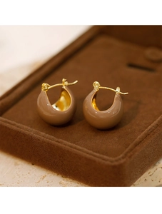 Détail de créoles dorées en émail marron sur un plateau à bijoux en velours