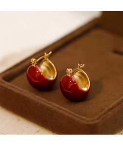 Vue détaillée de boucles d'oreilles en émail rouge dans un écrin en velours