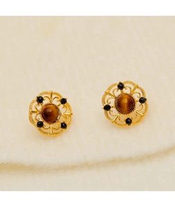 Detailed shot of gold-tone hollow earrings with tiger eye stone and black crystal accents